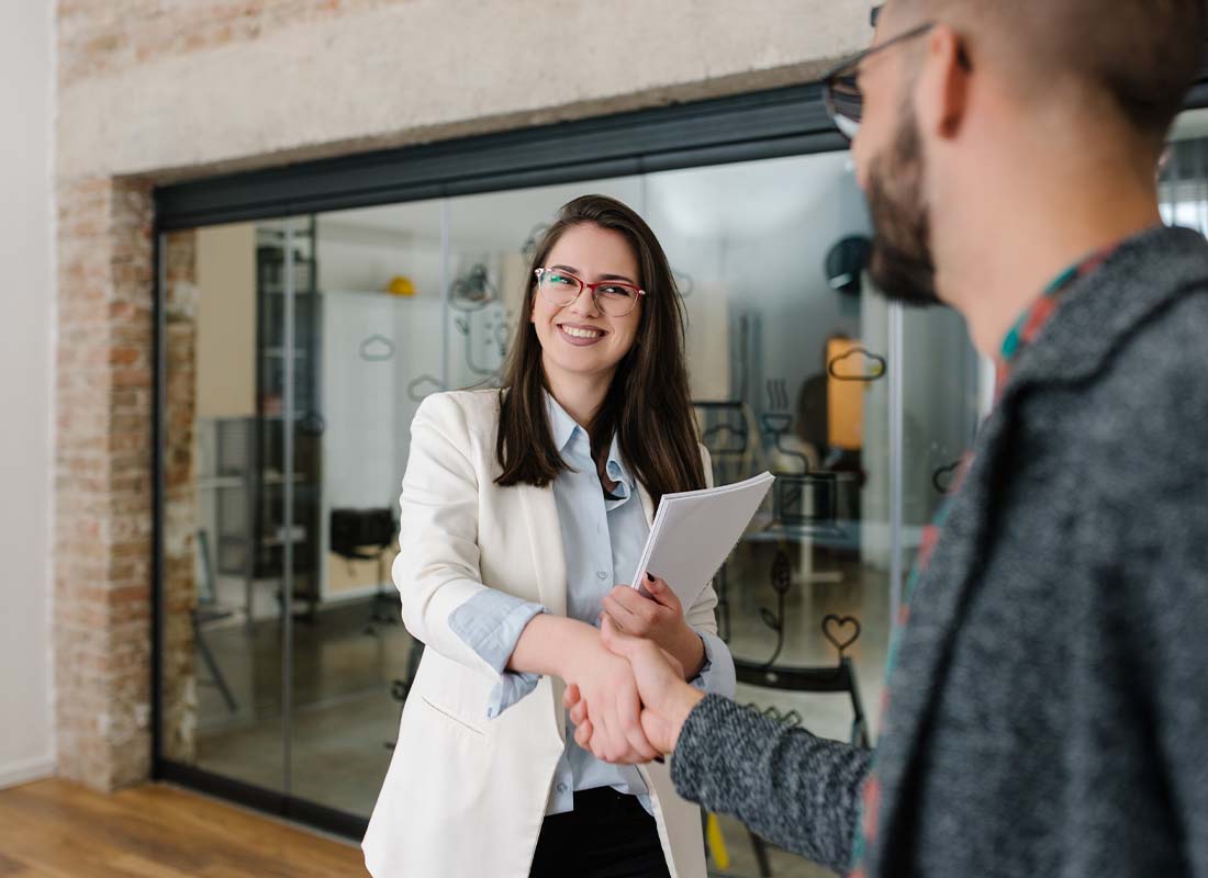 Staffing Agency Insurance - Warm Welcome and Handshake Between a Potential Business Hire for a Job Interview With a Staffing Agency in a Modern Office